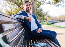  Suresh MacKenzie studied the Diploma of Leadership and Management BSB50420 sitting on a wooden bench with a book beside him.